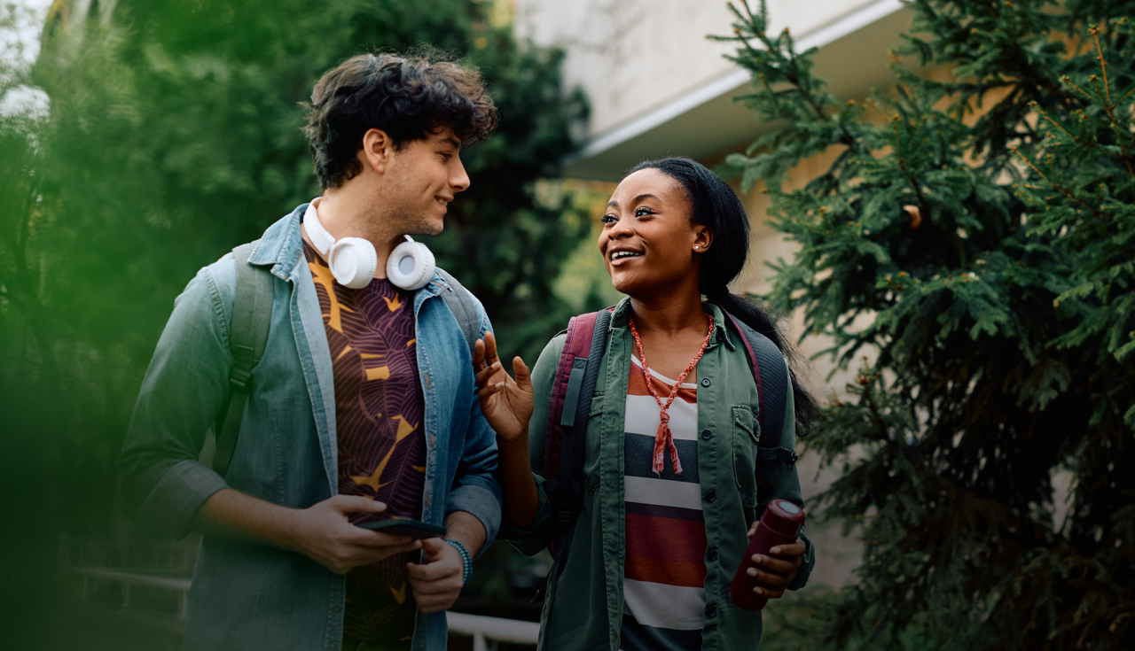 Image of 2 students walking and talking on campus.