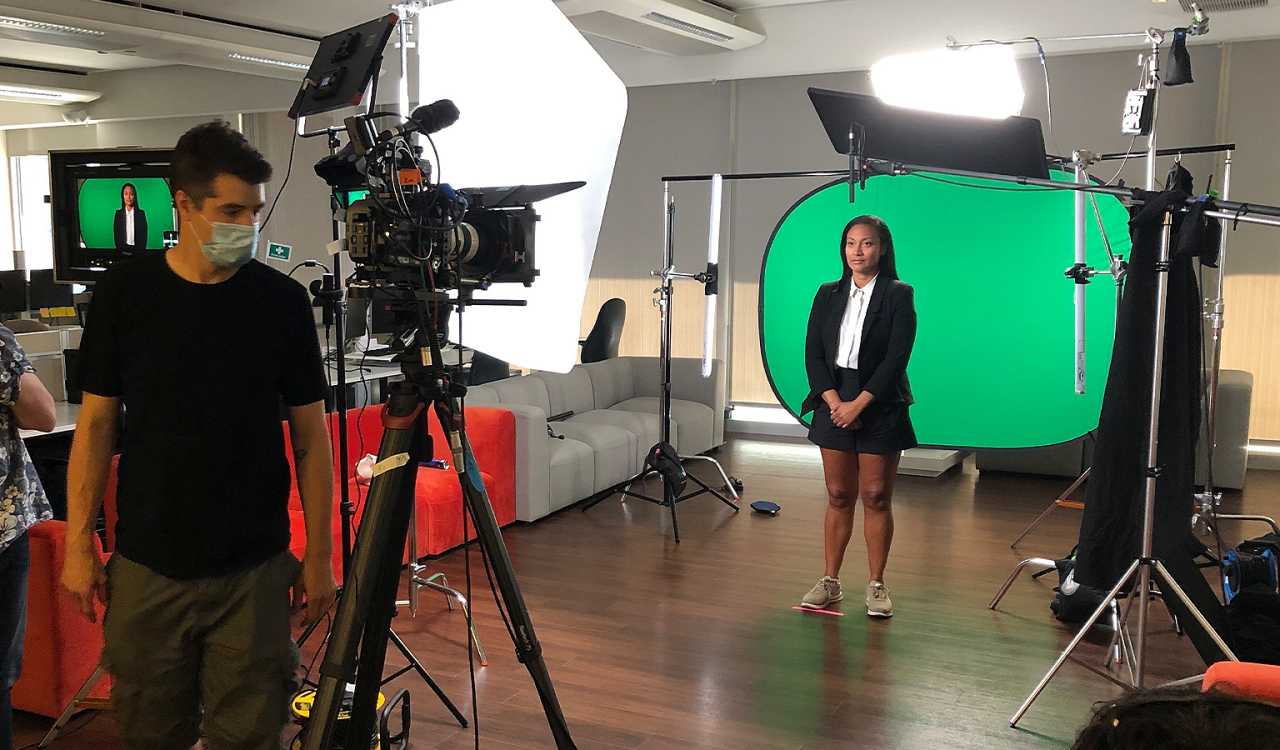 Film crew in in front of green screen with actor.