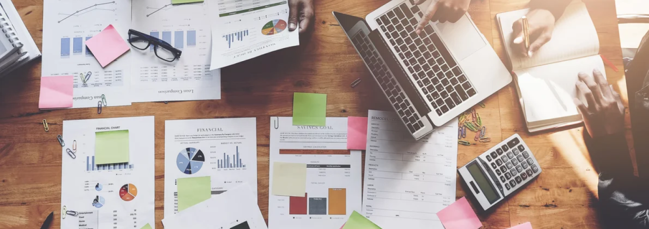 Business individuals using a laptop and paperwork to carry out their work responsibilities.