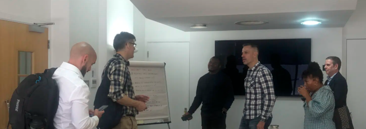 Members of the roundtables chatting and putting ideas onto a whiteboard.