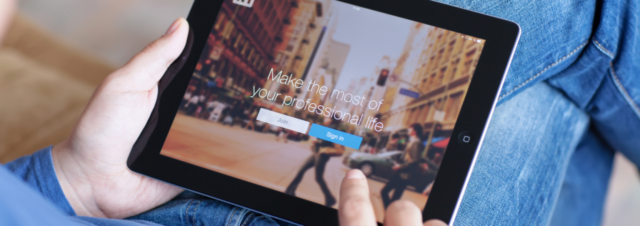 A person browsing the internet on an iPad, using the device's touchscreen to navigate through LinkedIn's website.