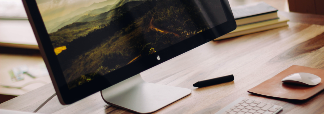 A computer monitor placed on a desk, displaying a landscape background.