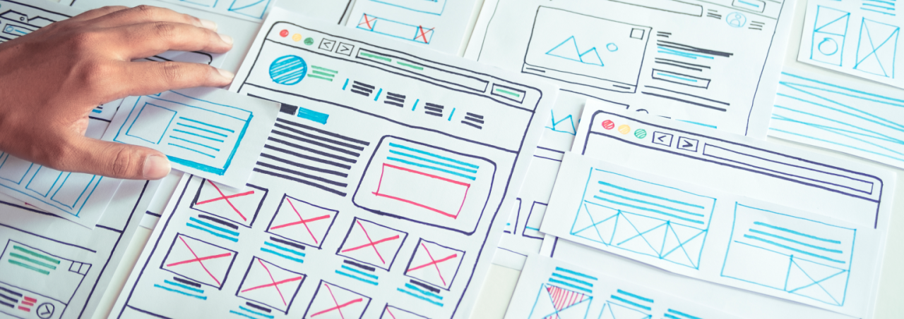 An individual indicating a website design on a piece of paper, demonstrating their involvement in the world of web development.